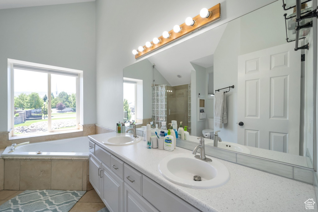 Bathroom with double vanity, tile patterned flooring, a bath, a tile shower, and vaulted ceiling