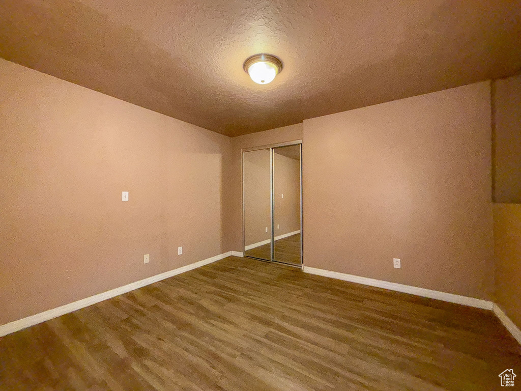 Unfurnished bedroom featuring wood finished floors, a textured ceiling, and a closet
