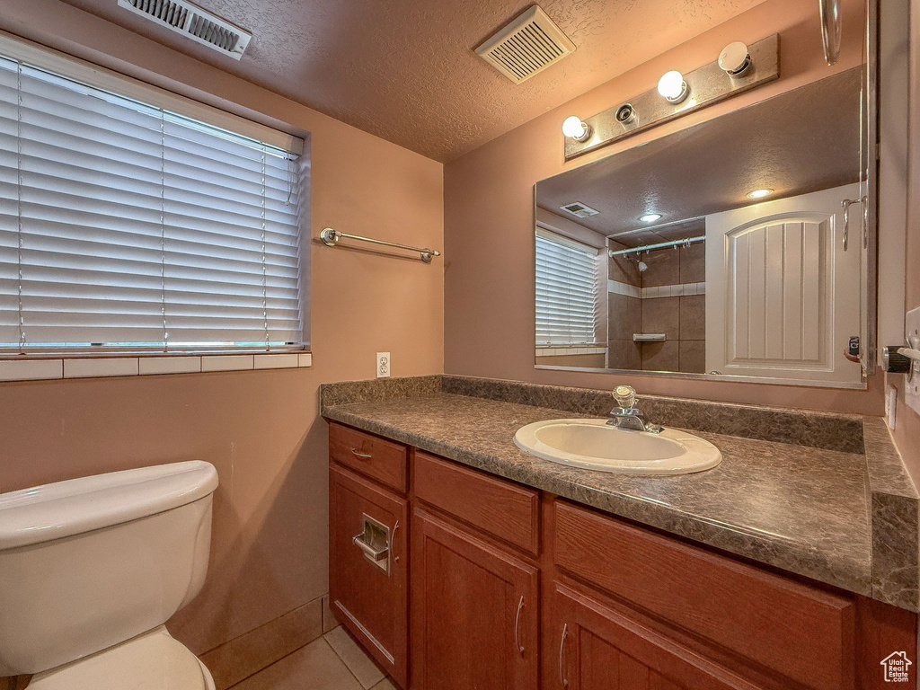 Bathroom with vanity, a shower, tile patterned floors, and a textured ceiling