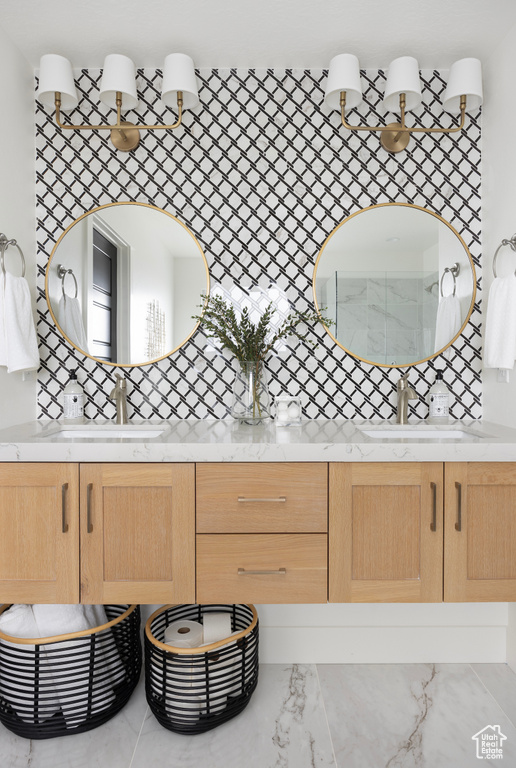 Full bath featuring tasteful backsplash, double vanity, and marble look tiles
