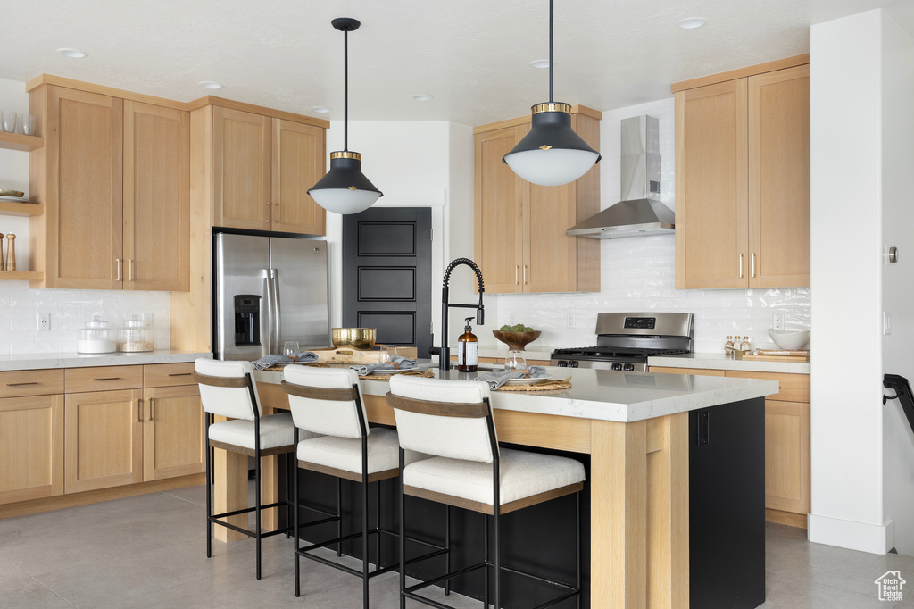 Kitchen featuring wall chimney range hood, stainless steel appliances, light brown cabinetry, tasteful backsplash, and recessed lighting