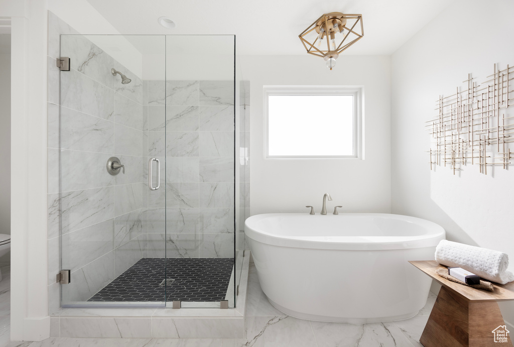 Bathroom with a soaking tub, marble finish floors, and a stall shower