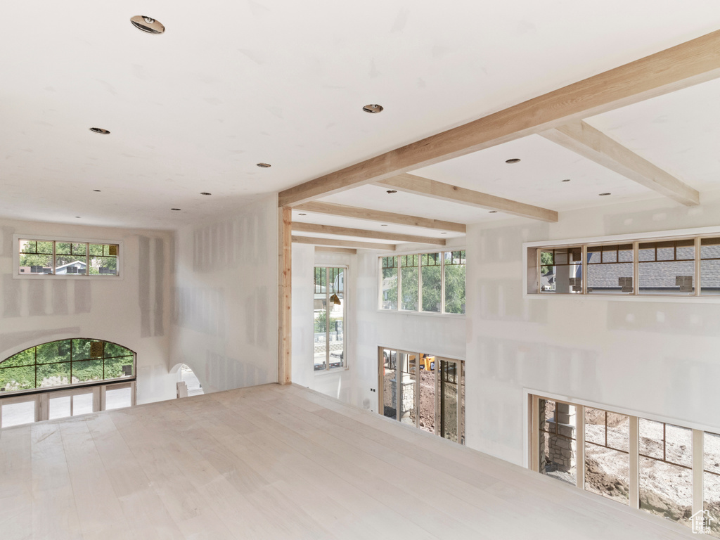 Unfurnished living room with plenty of natural light, beamed ceiling, and recessed lighting