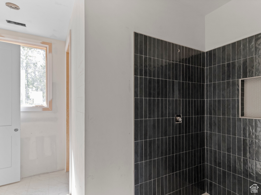Bathroom with tiled shower and marble look tiles