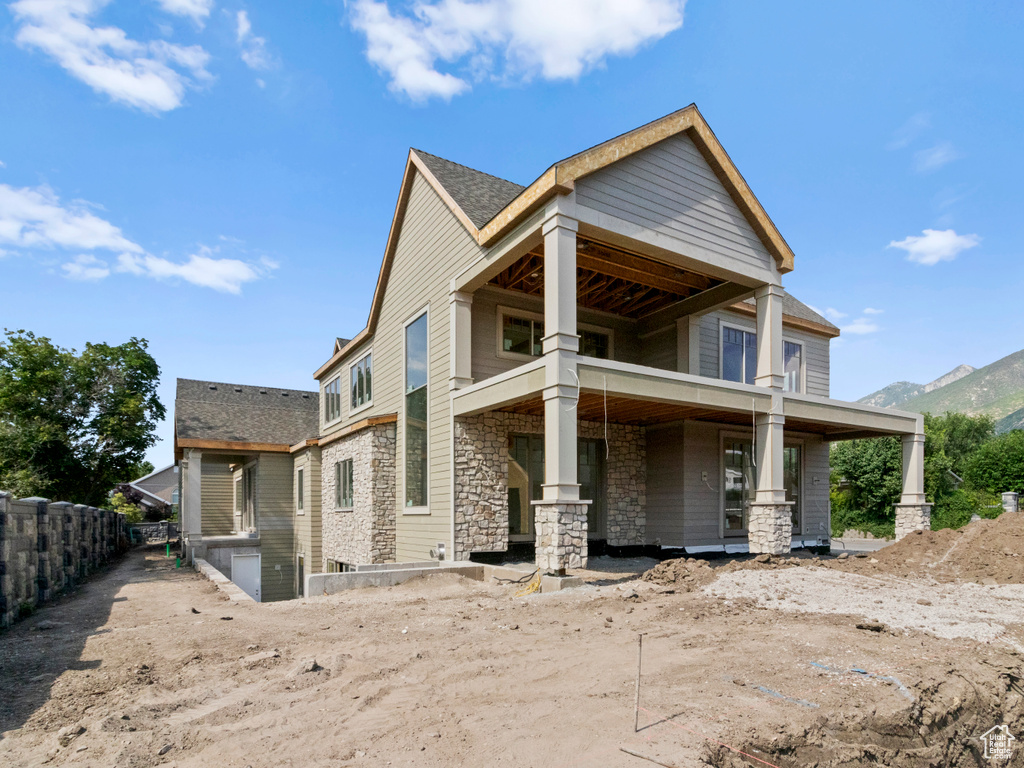 Rear view of property with stone siding, covered porch, a mountain view, and a balcony