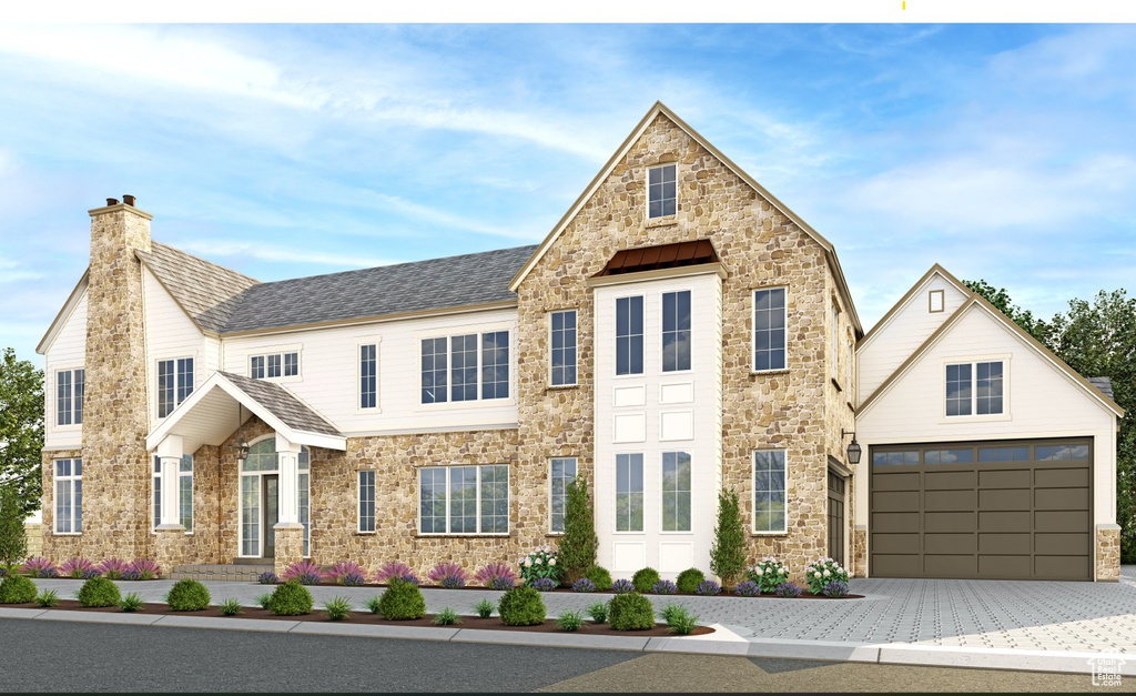 View of front facade with stone siding, a chimney, and driveway