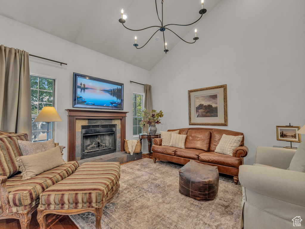 Living room with a chandelier, high vaulted ceiling, a fireplace, and wood finished floors