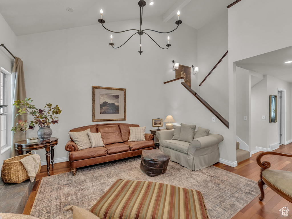 Living area with stairs, a towering ceiling, wood finished floors, and a chandelier