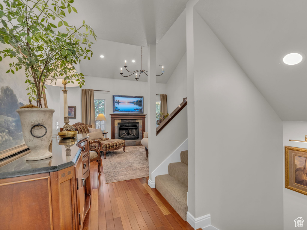 Entryway featuring vaulted ceiling, light wood-style floors, a tiled fireplace, recessed lighting, and stairway