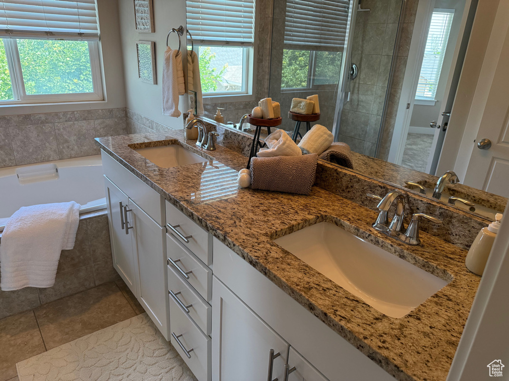 Full bath with healthy amount of natural light, double vanity, and a shower stall