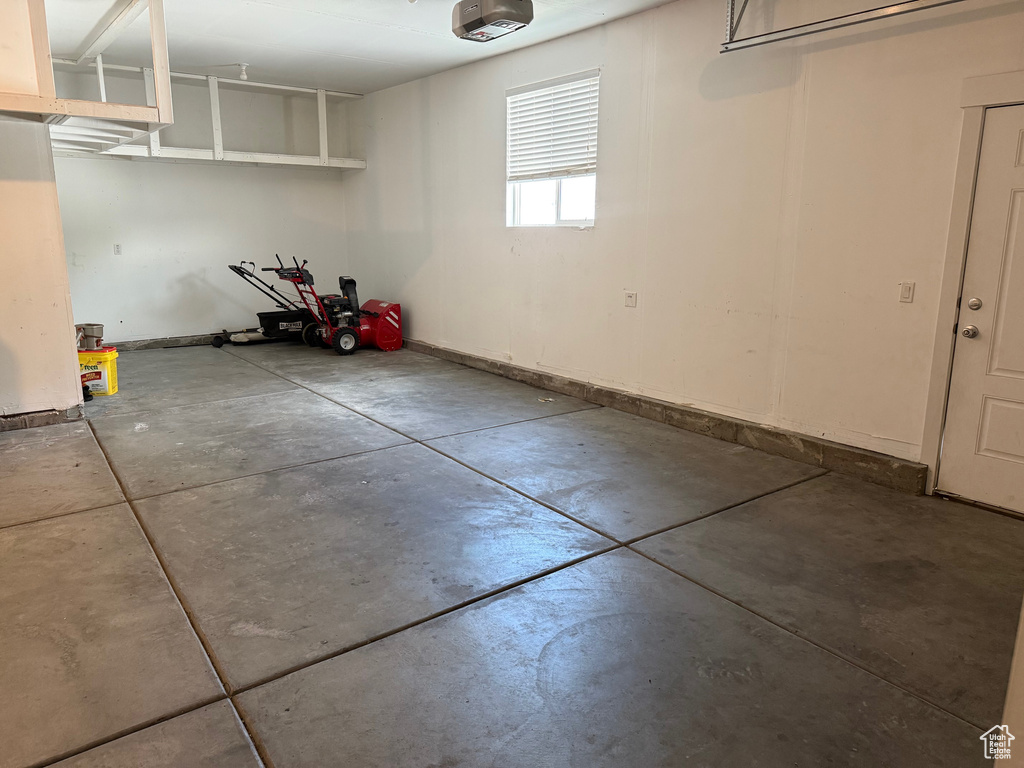Garage featuring a garage door opener and baseboards