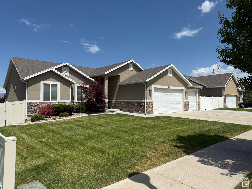 View of front of property with stone siding, stucco siding, a garage, driveway, and roof with shingles