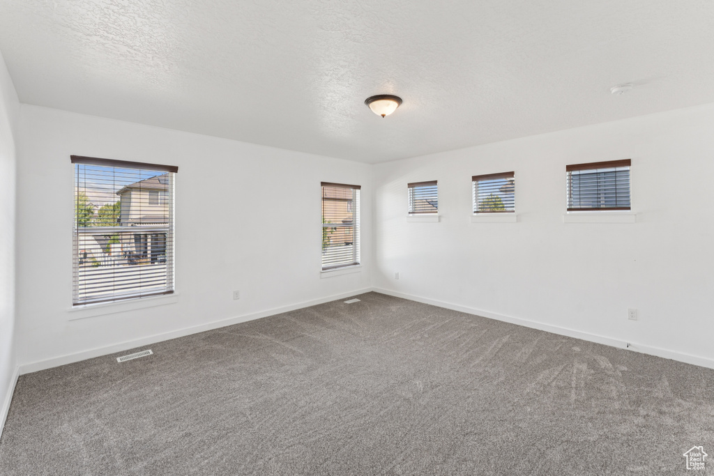 Spare room with dark carpet and a textured ceiling