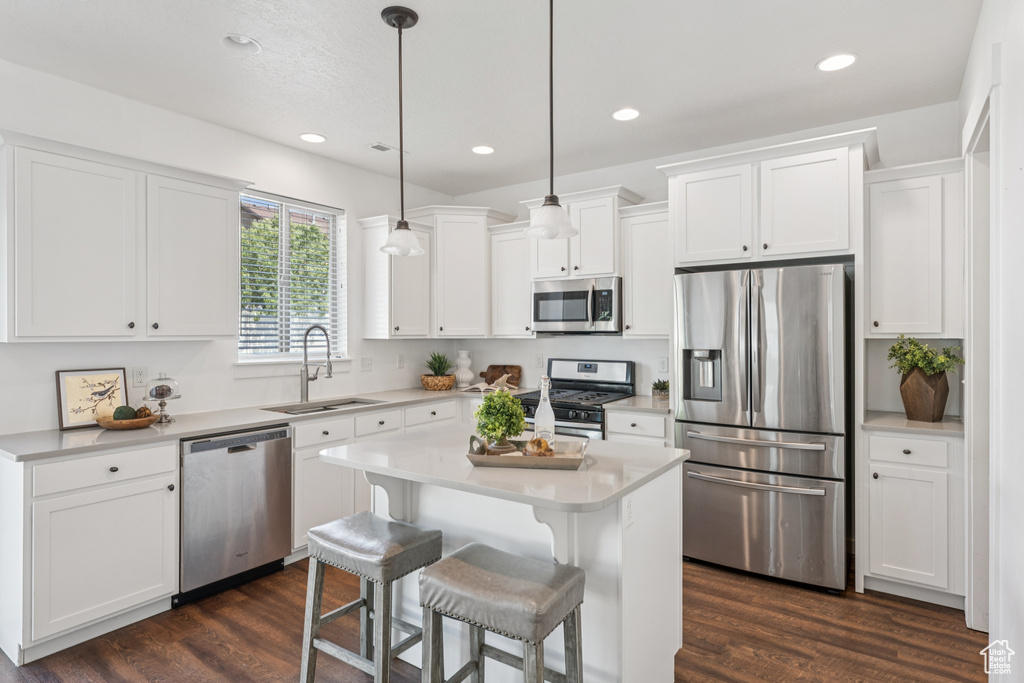 Kitchen featuring appliances with stainless steel finishes, white cabinetry, light countertops, dark wood-style flooring, and recessed lighting