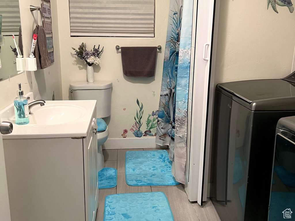 Bathroom featuring vanity, separate washer and dryer, wood tiled floors, and a shower with curtain