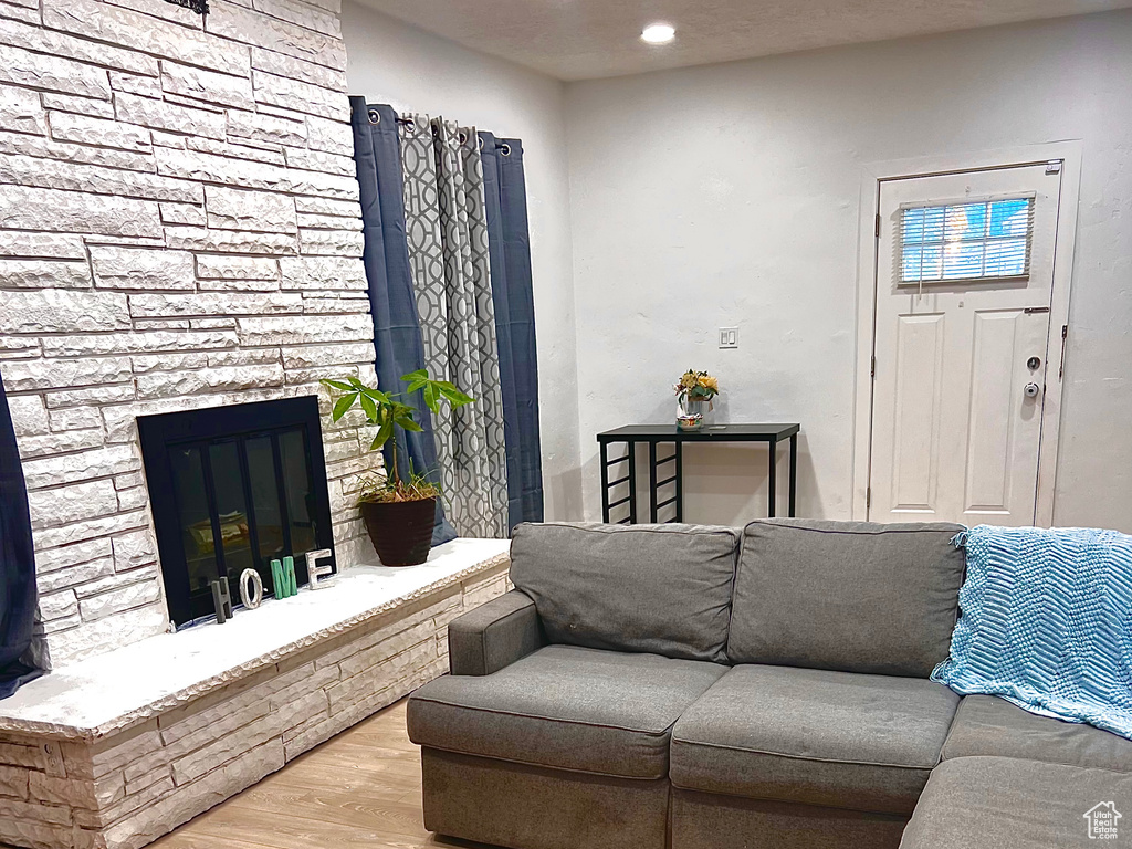 Living room with wood finished floors, recessed lighting, and a stone fireplace