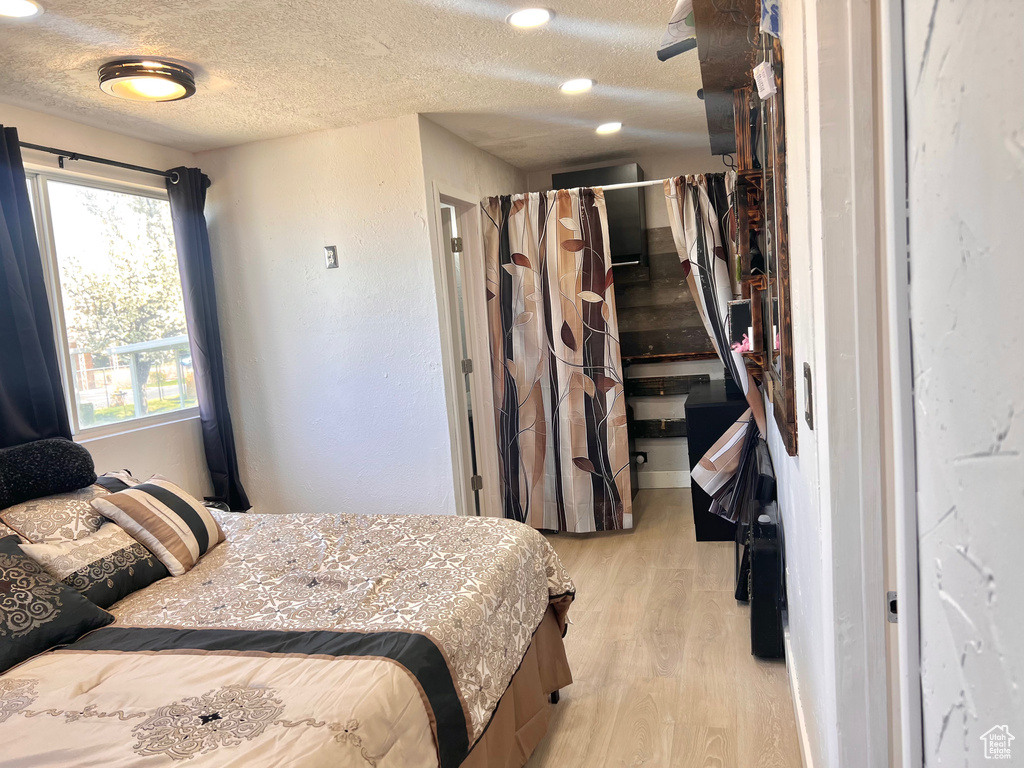 Bedroom with light wood-type flooring and a textured ceiling