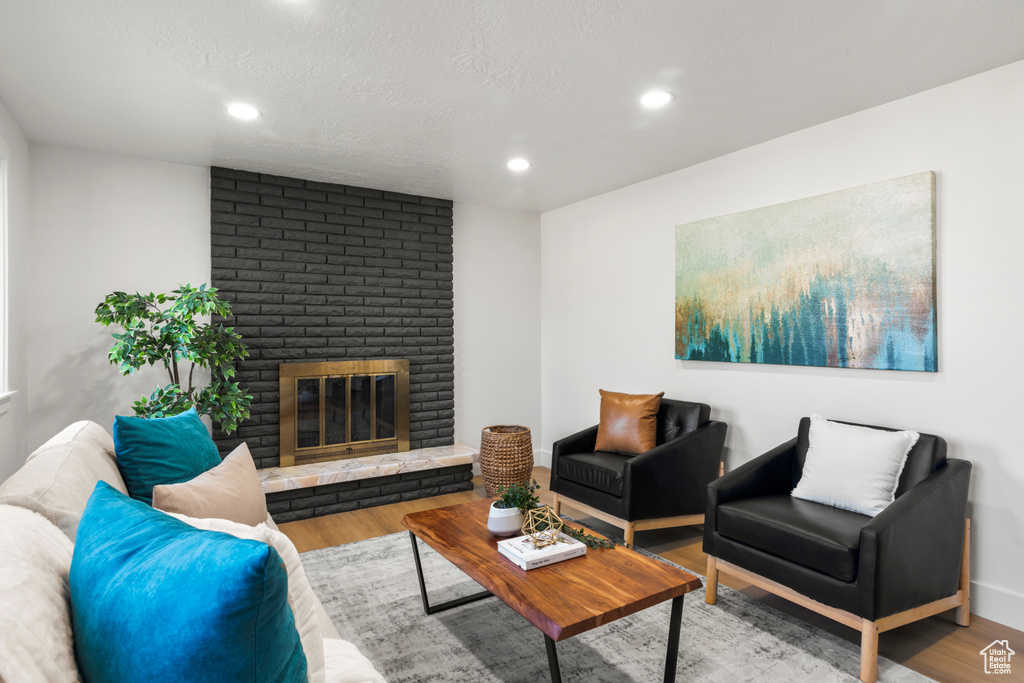 Living room with wood finished floors, recessed lighting, and a fireplace