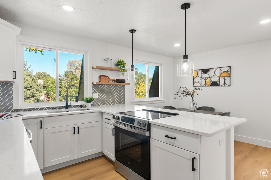 Kitchen with stainless steel electric stove, tasteful backsplash, light wood-style flooring, a peninsula, and recessed lighting