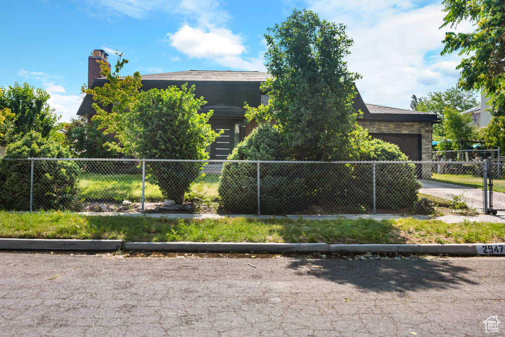 View of front of home featuring an attached garage, a chimney, and driveway