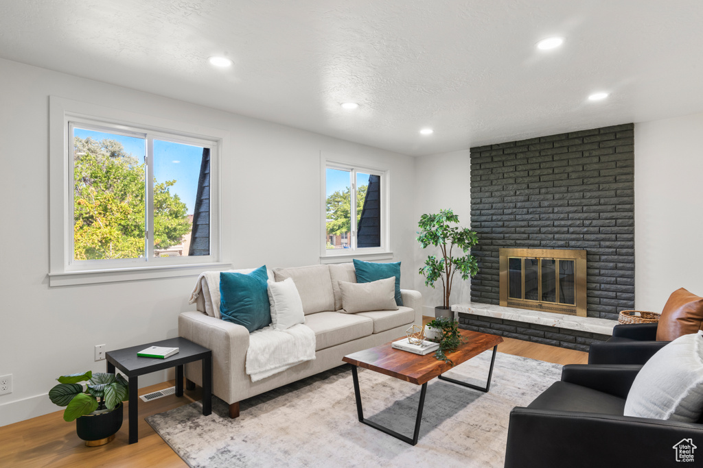 Living room with wood finished floors, healthy amount of natural light, recessed lighting, a fireplace, and a textured ceiling