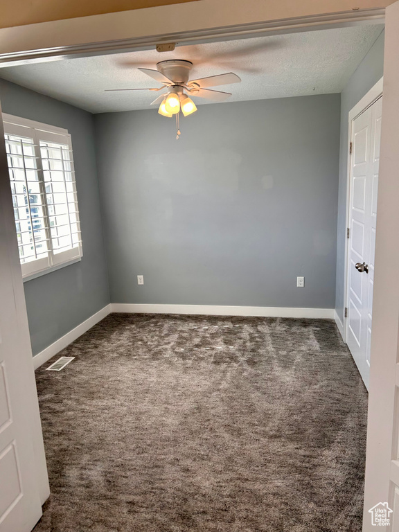 Carpeted empty room featuring a ceiling fan and a textured ceiling