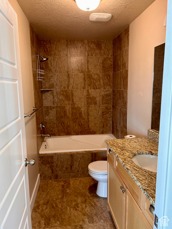 Bathroom with vanity, tiled shower / bath, a textured ceiling, and tile patterned floors