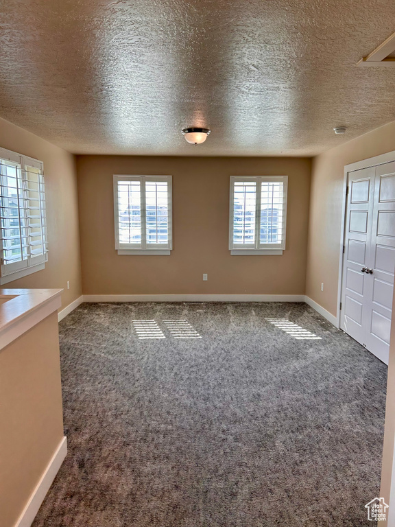 Carpeted spare room featuring plenty of natural light and a textured ceiling