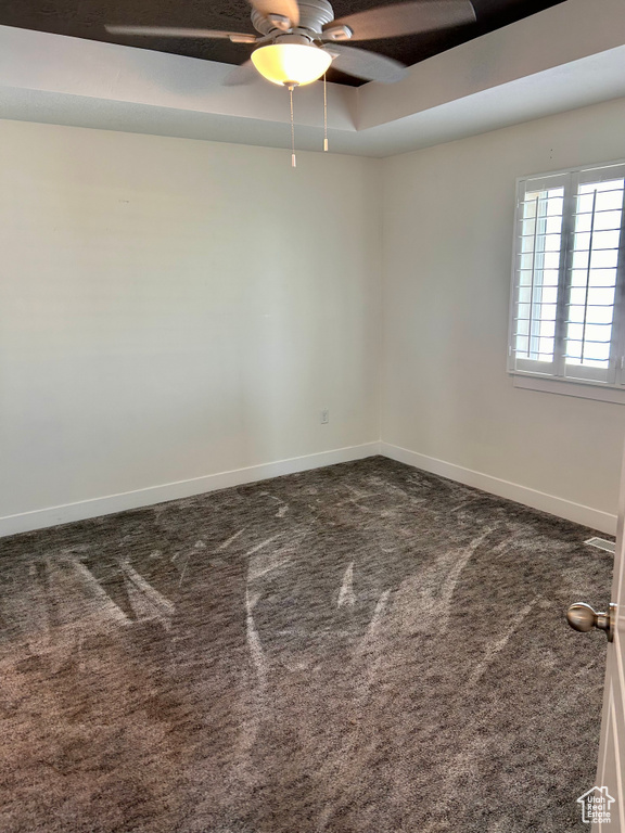 Spare room with a ceiling fan and dark carpet