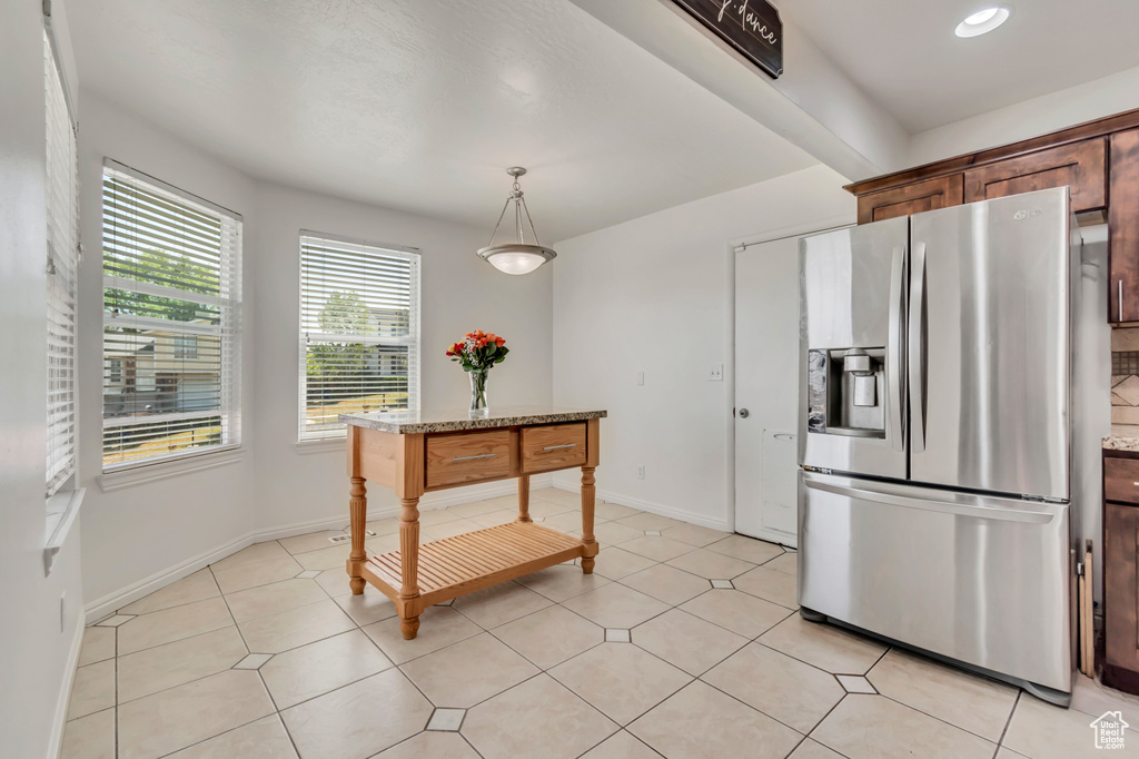 Kitchen with stainless steel fridge, decorative light fixtures, light tile patterned floors, and recessed lighting