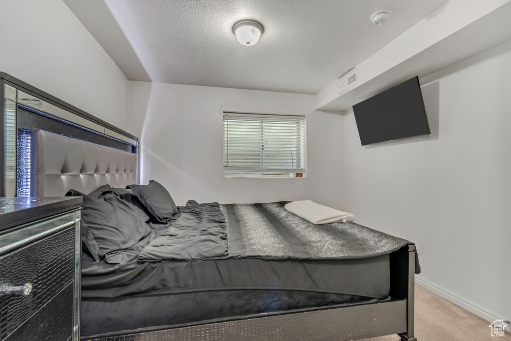 Carpeted bedroom featuring a textured ceiling and baseboards