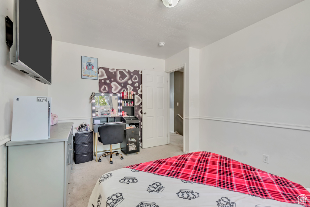 Bedroom with light colored carpet and a desk