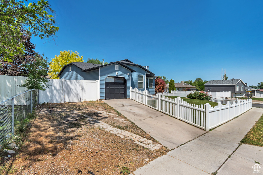 View of front of home with a fenced front yard, concrete driveway, and an attached garage
