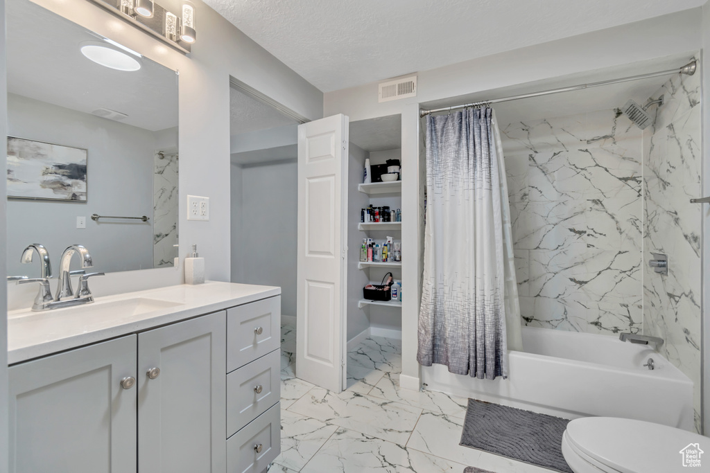 Bathroom featuring marble finish flooring, vanity, and shower / bath combo with shower curtain