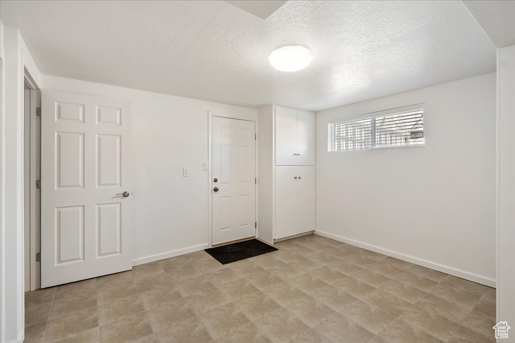 Foyer entrance featuring a textured ceiling and baseboards