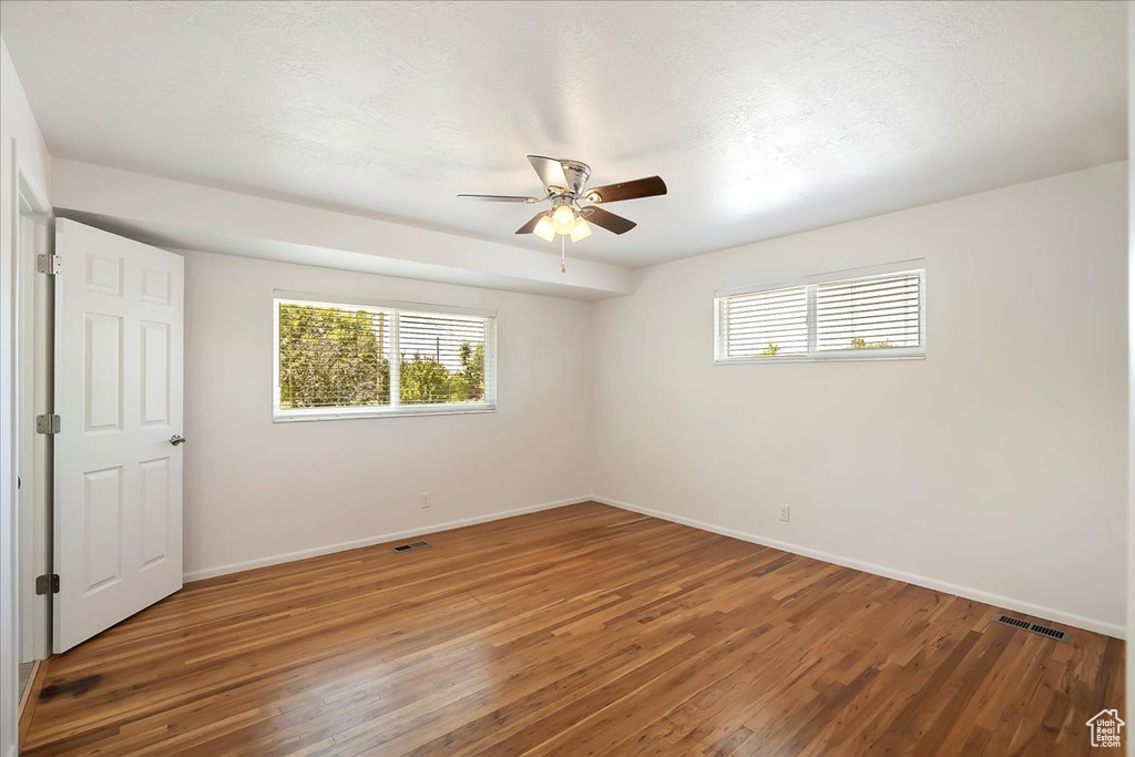 Unfurnished bedroom with multiple windows, wood finished floors, and a ceiling fan
