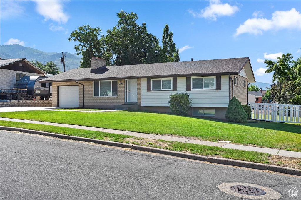 View of front of property with a mountain view, a garage, concrete driveway, and a chimney