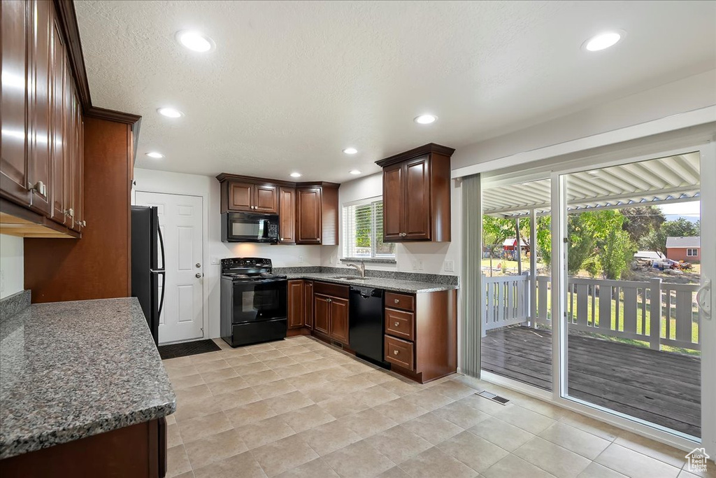 Kitchen featuring black appliances, recessed lighting, dark stone countertops, a textured ceiling, and light tile patterned flooring