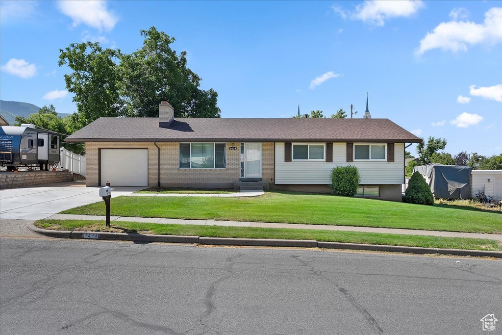 View of front facade featuring concrete driveway, an attached garage, a chimney, and brick siding
