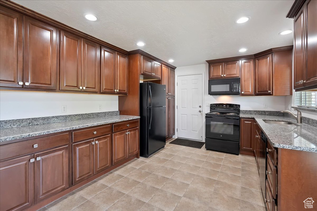 Kitchen with black appliances, light stone counters, and recessed lighting
