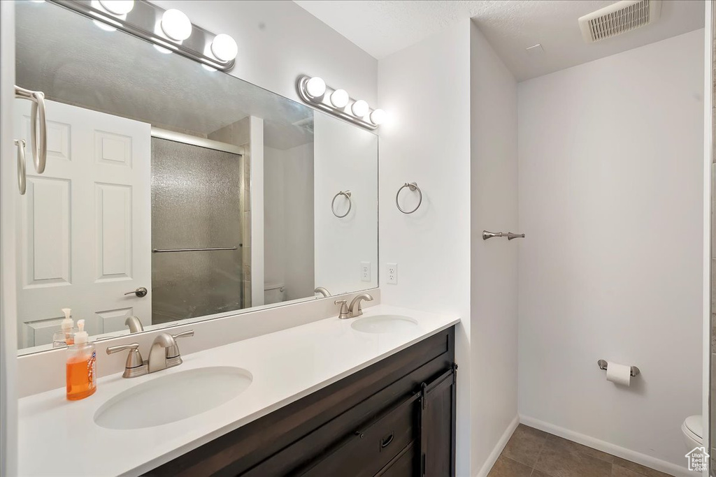 Full bathroom with double vanity, a stall shower, and tile patterned flooring