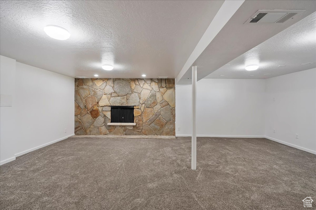 Finished below grade area featuring a textured ceiling, carpet, and a fireplace