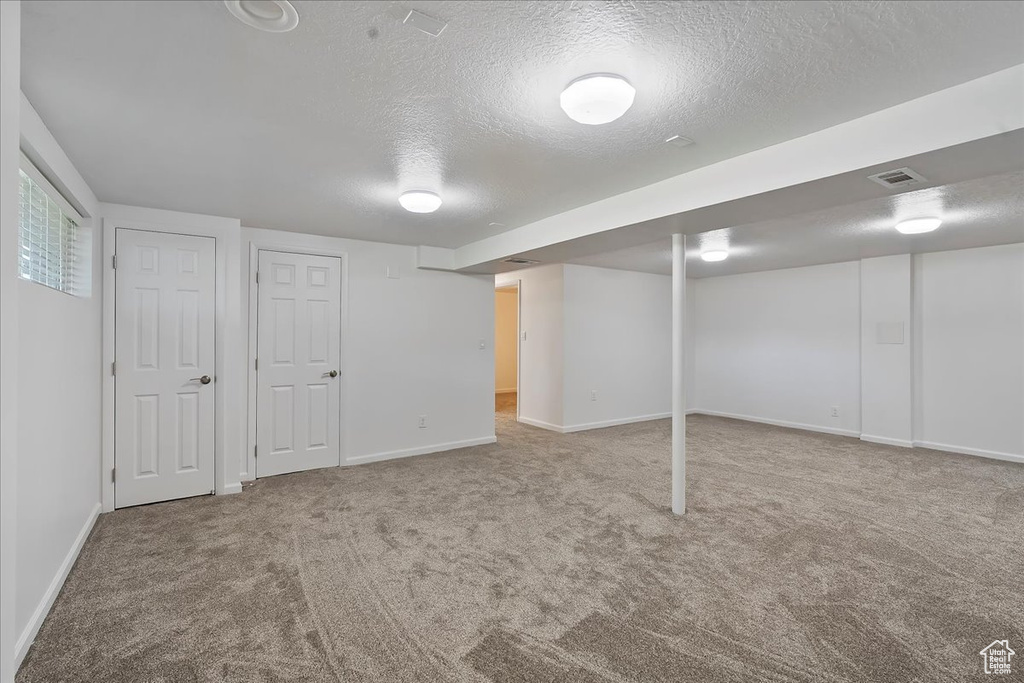 Basement with a textured ceiling and carpet