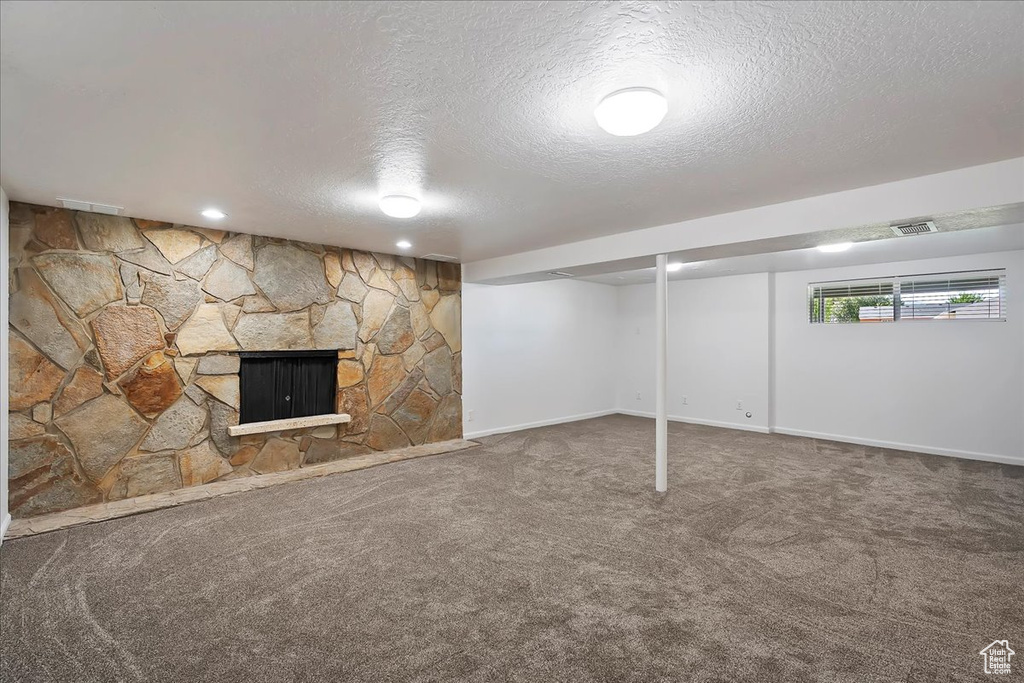Below grade area featuring a textured ceiling, carpet flooring, and a fireplace