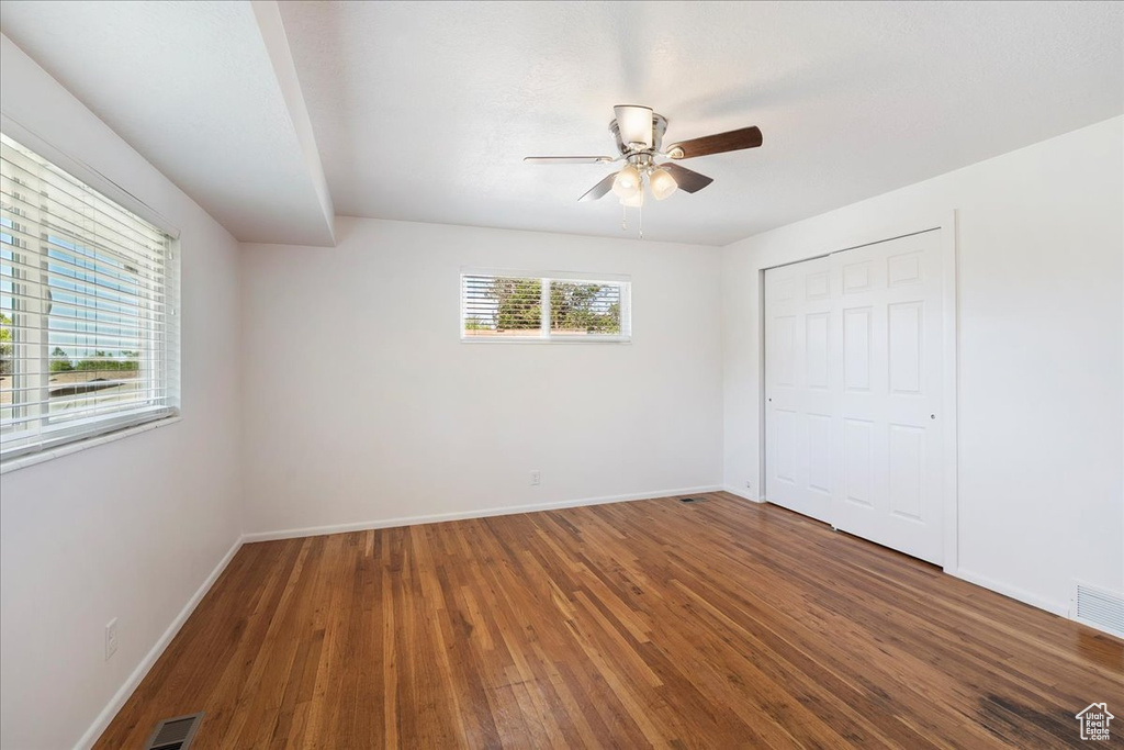 Unfurnished bedroom featuring wood finished floors, a closet, and ceiling fan