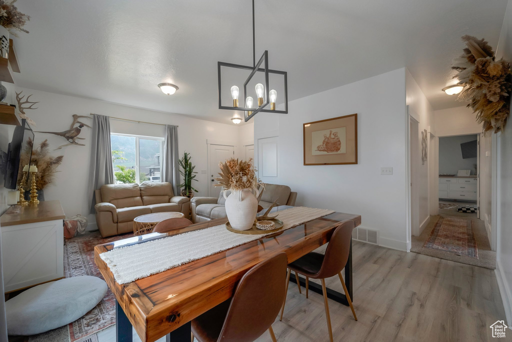 Dining area with light wood-type flooring and a chandelier