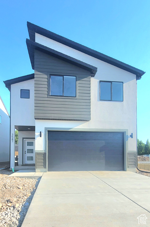 Contemporary home featuring an attached garage, stucco siding, and concrete driveway