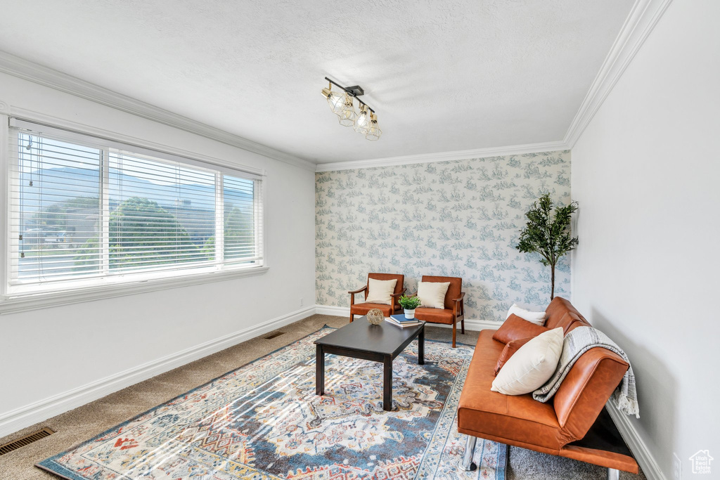Living area with ornamental molding, carpet flooring, and wallpapered walls