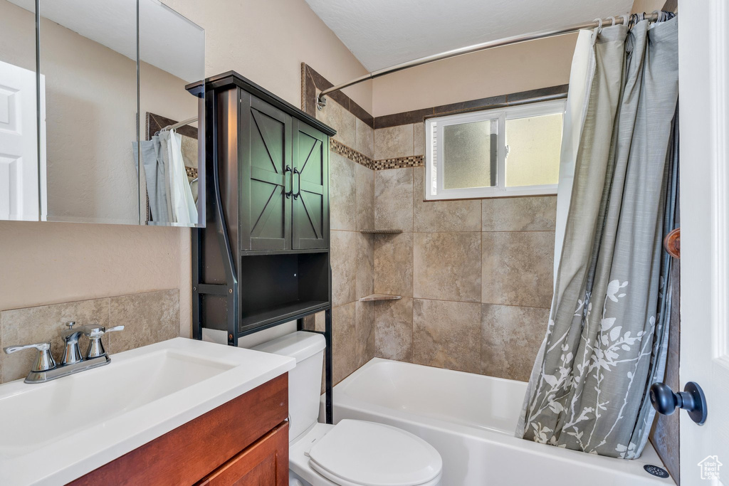 Full bath featuring shower / bathtub combination with curtain, vanity, and backsplash