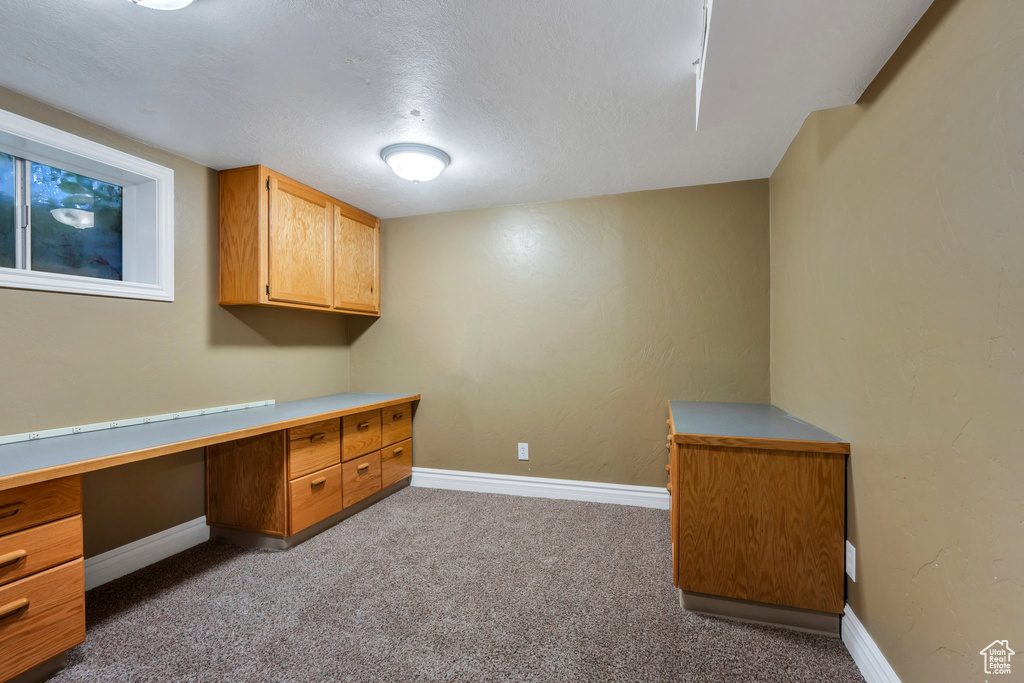 Unfurnished office with dark colored carpet and built in study area